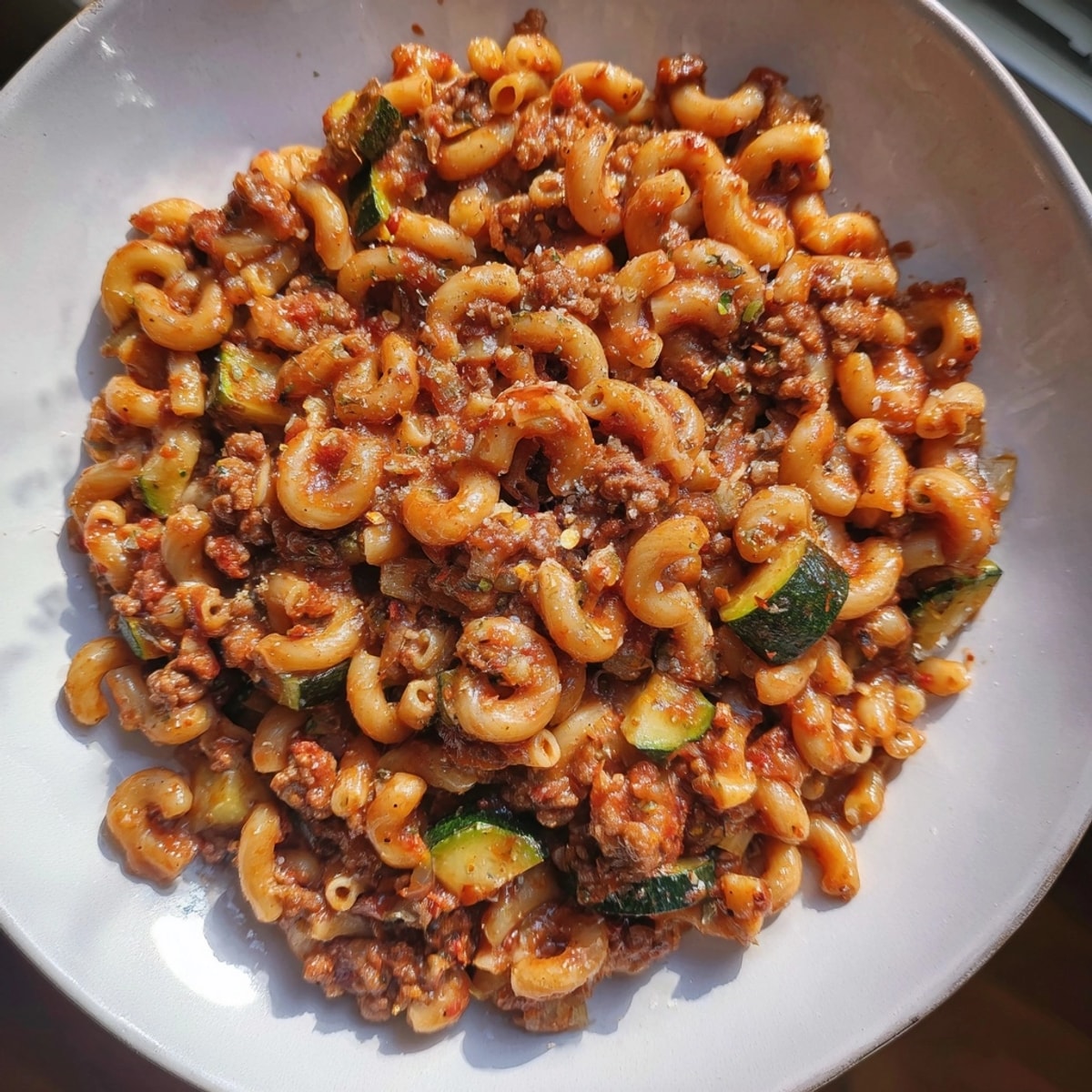 A colorful bowl of Healthy Beef Pasta with roasted vegetables, steam rising.