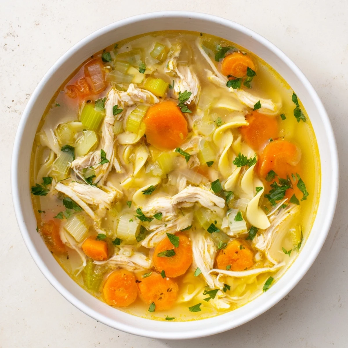 Steaming bowl of homemade chicken noodle soup, with visible carrots and tender chicken, ready to enjoy.