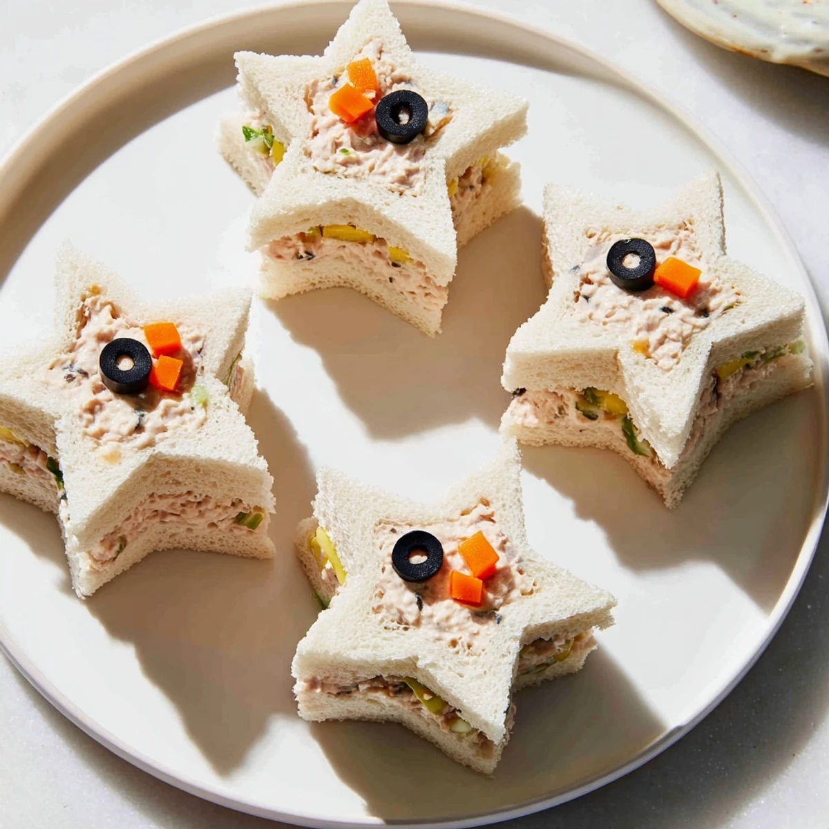 Brightly decorated Mini Starfish Sandwiches with olives, capers, and a hint of diced carrot, perfect for any occasion.