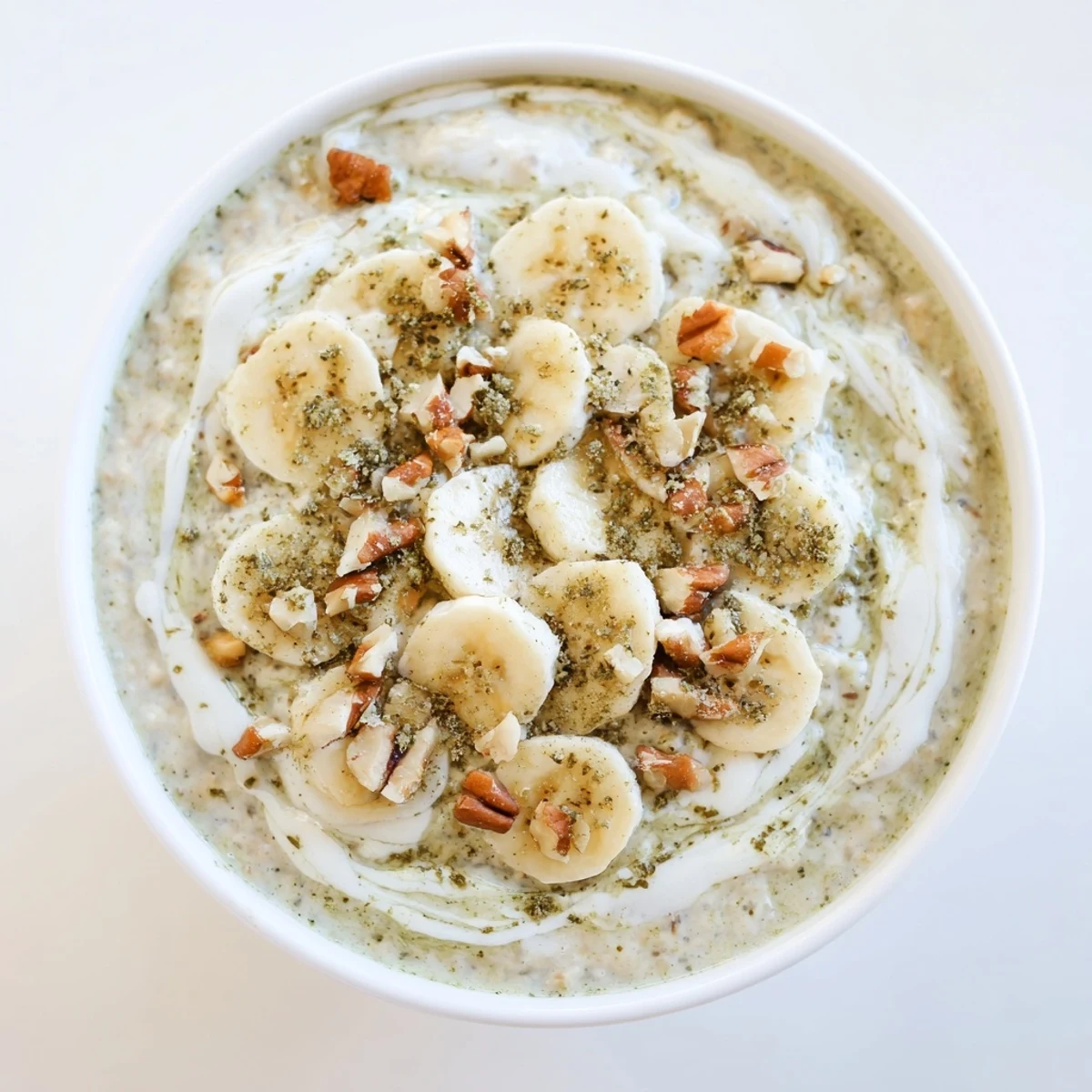 Creamy High-Protein Eggnog Matcha Overnight Oats with banana slices and toasted coconut flakes.