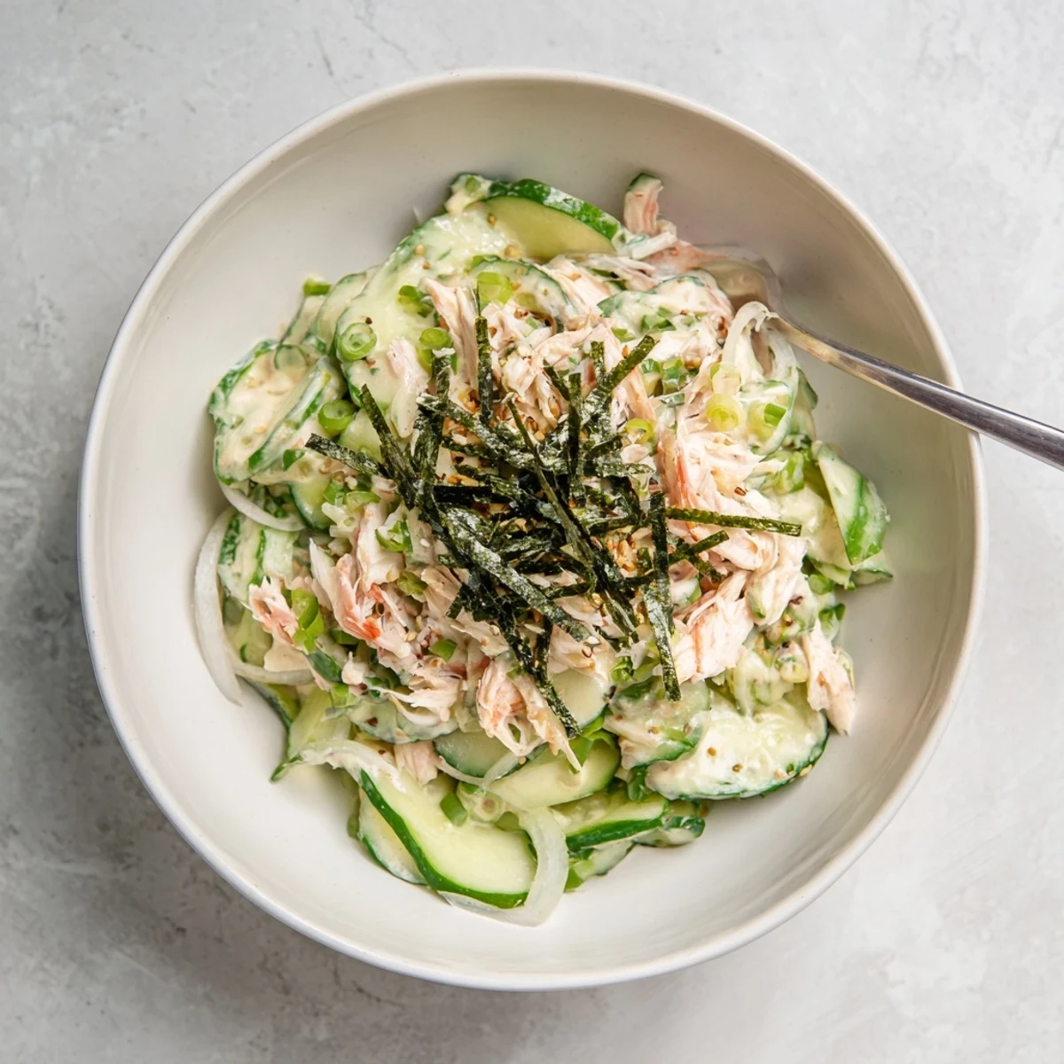 A refreshing California Roll Cucumber Salad with crisp cucumbers, shredded imitation crab, and creamy mayo, topped with sesame seeds and nori strips.