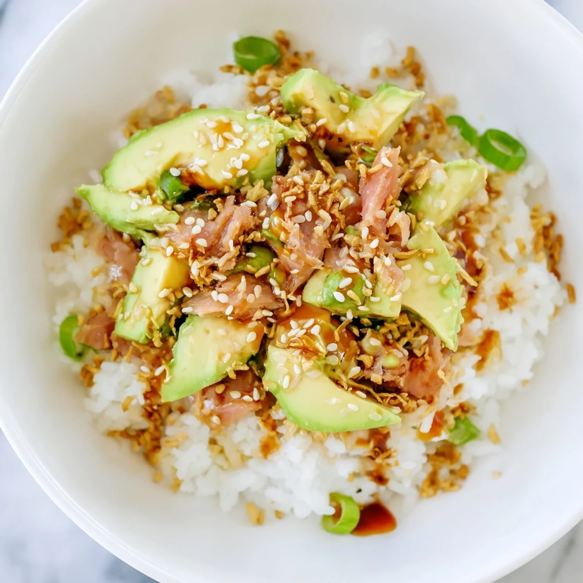 This Tuna Avocado Rice Bowl features crisp cucumber, scallions, and a drizzle of sesame-ginger dressing for a fusion flavor.