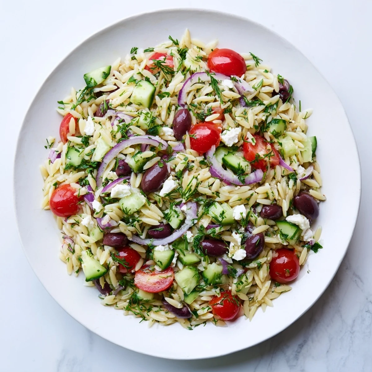 A vibrant bowl of Greek Orzo Salad with feta, cucumbers, tomatoes, and olives tossed in a zesty lemon-oregano dressing.