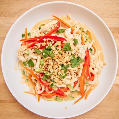 A large bowl of Thai-Inspired Peanut Chicken Pasta, noodles coated in creamy peanut sauce.