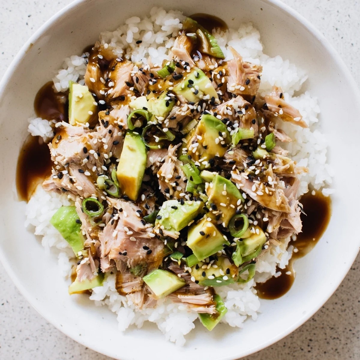 A close-up view of a vibrant Tuna Avocado Rice Bowl with fluffy jasmine rice, diced tuna, and creamy avocado slices.