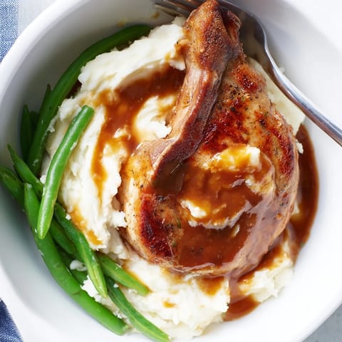 Creamy cheddar mash bowl topped with succulent pork chops and vibrant green beans.  
