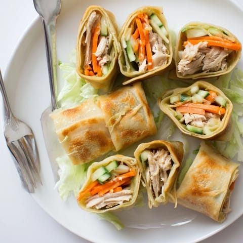 A close-up of garlicky pulled chicken wraps glistening with buttery garlic sauce on a rustic plate.  