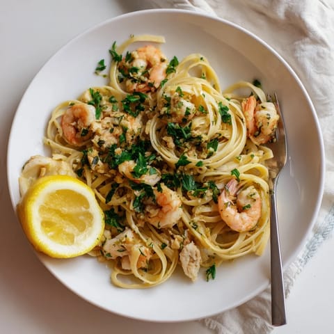 Steaming platter of Lemon Garlic Shrimp & Chicken Pasta, garnished with lemon wedges and parsley on a rustic table.