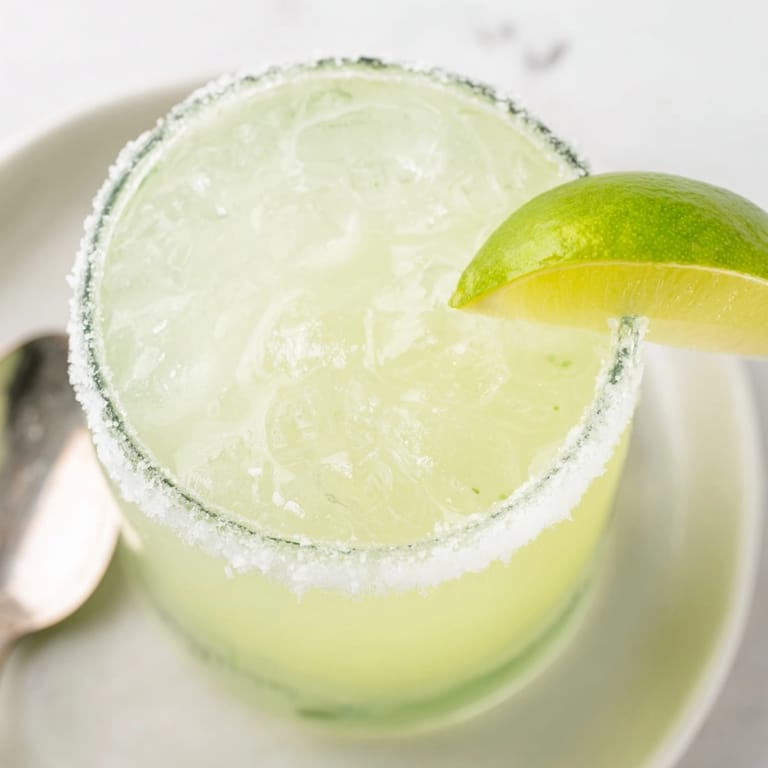 Chilled classic margarita in a salt-rimmed glass, garnished with a lime wedge.