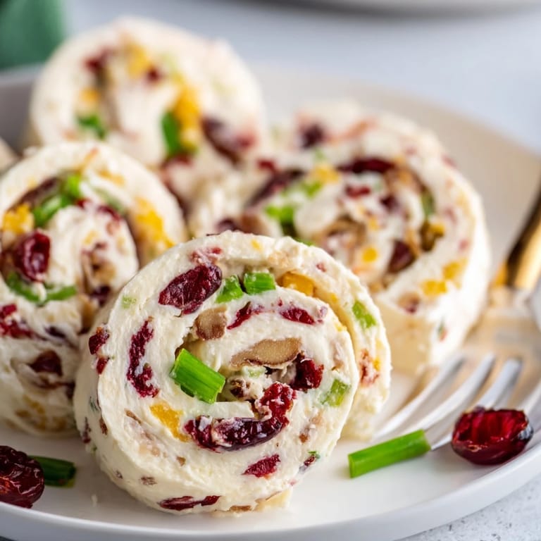 Colorful pinwheels filled with cream cheese, cranberries, and jalapeños, perfect for parties.  