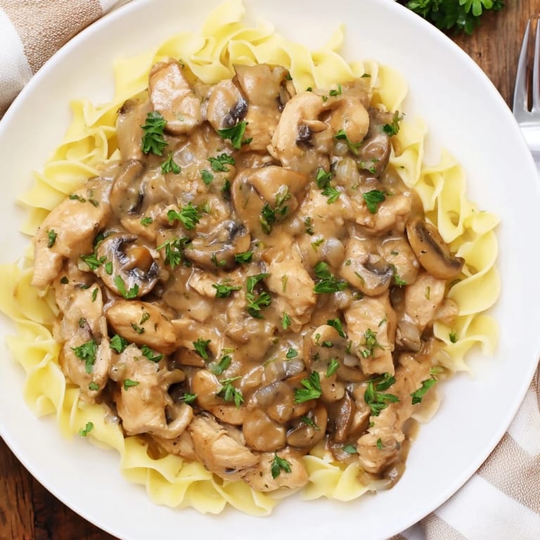 Enjoy a warm bowl of creamy chicken stroganoff, served hot over fluffy egg noodles for dinner.