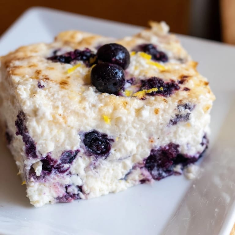 Fluffy Blueberry Cottage Cheese Bake, speckled with vibrant blueberries, ready to be sliced and served.